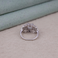 Silver ring with a diamond on a beige surface