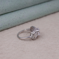 Silver ring with diamond accents on a light gray surface
