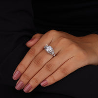 Hand wearing a silver ring with a large diamond on a black background