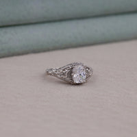 Silver ring with a large diamond on a beige surface