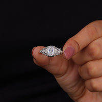 Hand holding a diamond ring against a black background