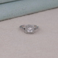 Silver ring with a diamond on a light gray surface, Classic Double Halo Wedding Band, Brilliant Cushion Cut Moissanite Bridal Jewelry, Eco Friendly Engagement Ring For Brides
