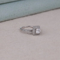 Silver ring with a diamond on a light gray surface, Double Halo Split Shank Cushion Moissanite Ring, Cushion Cut Moissanite Engagement Ring, Split Shank Bridal Ring