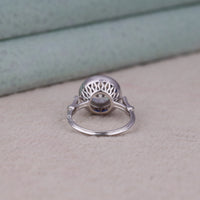 Silver ring with a textured design on a light gray surface, Antique Inspired Blue Sapphire Halo Ring – Art Deco Round CZ Target Ring