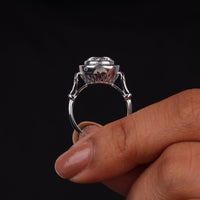 Silver ring held between fingers against a black background, Art Deco Vintage Target Ring – Round CZ Stone with Blue Sapphire Halo