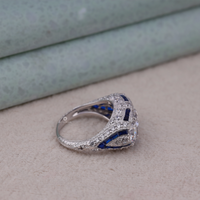 Silver ring with blue gemstones on a beige surface