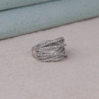 Silver ring with gemstones on a light gray surface, Modern Moissanite Stacking Ring, Sparkling Round Moissanite Cocktail Ring, Unique Criss Cross Bridal Band, 14K Gold Moissanite Party Ring