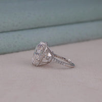 Diamond ring with a large central gemstone and smaller stones on a neutral background, Brilliant Heart Moissanite Proposal Jewelry, Chic Round Halo With Heart Center Engagement Ring