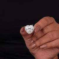 Heart-shaped diamond ring held by a hand against a black background, Romantic Heart & Round Moissanite Ring with Halo | Moissanite Engagement Jewelry