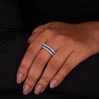 Hand wearing a ring with blue gemstone on a dark background
