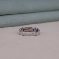 Silver ring with blue stones on a beige surface