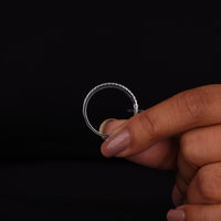 Hand holding a silver ring against a black background