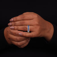 Close-up of a hand wearing a ring with a black background