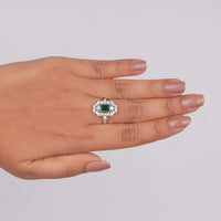 Hand wearing a diamond ring with a green gemstone on a light gray background, Glamorous Art Deco Inspired Engagement Ring, Conflict Free Cubic Zirconia Bridal Jewelry