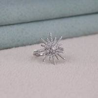 Silver star-shaped ring with gemstones on a light gray surface