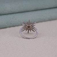 Silver ring with star-like design on a textured surface