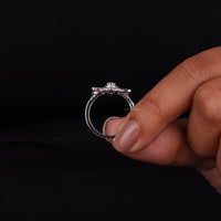 Silver ring with a diamond held between fingers against a black background