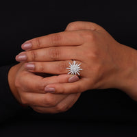 Hand wearing a diamond ring with a black background