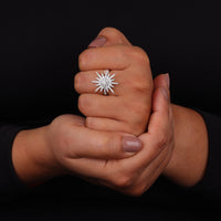 Close-up of a hand wearing a star-shaped diamond ring against a black background