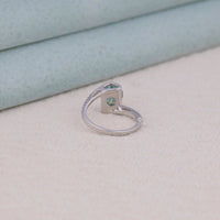 Silver ring with a green gemstone on a light beige surface