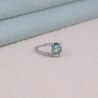 Silver ring with a green gemstone on a light background
