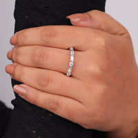 Close-up of a hand wearing a silver ring with small stones on a neutral background, Minimalist Moissanite Wedding Ring, Timeless Baguette Eternity Band, Dainty Moissanite Band Ring