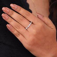 Hand wearing a silver ring with a black background, Round & Baguette Moissanite Dot Dash Eternity Band, Moissanite Eternity Band, Baguette and Round Moissanite Ring