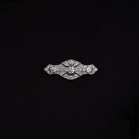 Art Deco vintage brooch featuring a round Cubic Zirconia center stone, blue accent stones, geometric design, and vintage-inspired styling.