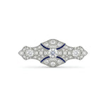 Art Deco vintage brooch featuring a round Cubic Zirconia center stone, blue accent stones, geometric design, and vintage-inspired styling.