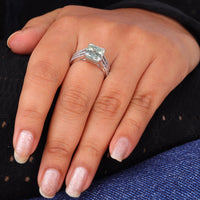 Asscher cut moissanite engagement ring with light green center stone, split shank pavé band, and elegant statement design