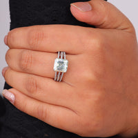 Asscher cut moissanite engagement ring with light green center stone, split shank pavé band, and elegant statement design