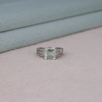 Asscher cut moissanite engagement ring with light green center stone, split shank pavé band, and elegant statement design