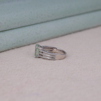 Asscher cut moissanite engagement ring with light green center stone, split shank pavé band, and elegant statement design