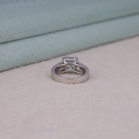 Asscher cut moissanite engagement ring with light green center stone, split shank pavé band, and elegant statement design