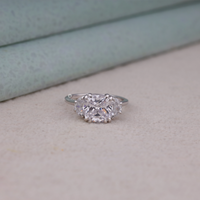 Cushion cut cubic zirconia three stone engagement ring with half moon side stones in a classic prong setting