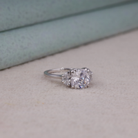 Cushion cut cubic zirconia three stone engagement ring with half moon side stones in a classic prong setting