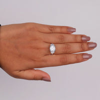 Cushion cut cubic zirconia three stone engagement ring with half moon side stones in a classic prong setting