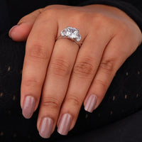 Cushion cut cubic zirconia three stone engagement ring with half moon side stones in a classic prong setting