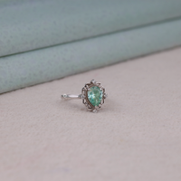 Green pear cut moissanite vintage engagement ring with decorative scrollwork accents and round accent stones