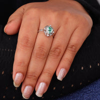 Green pear cut moissanite vintage engagement ring with decorative scrollwork accents and round accent stones