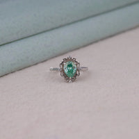 Green pear cut moissanite vintage engagement ring with decorative scrollwork accents and round accent stones