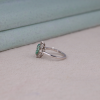 Green pear cut moissanite vintage engagement ring with decorative scrollwork accents and round accent stones