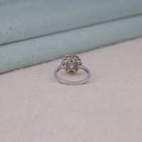 Green pear cut moissanite vintage engagement ring with decorative scrollwork accents and round accent stones