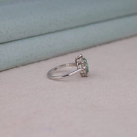 Green pear cut moissanite vintage engagement ring with decorative scrollwork accents and round accent stones