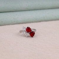 Heart cut Cubic Zirconia floral cluster ring featuring deep red center stones, clear marquise and pear accent stones, pavé band, elegant statement design.