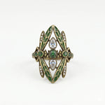Decorative ring with green gemstones and gold accents on a white background