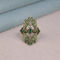 Decorative ring with green gemstones and gold accents on a soft surface