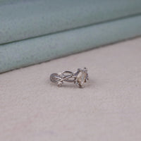 Nature-inspired vine ring featuring a kite cut cubic zirconia center stone with round accent stones and botanical leaf detailing