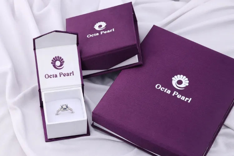 Purple jewelry box with 'Octa Pearl' branding on a white fabric background