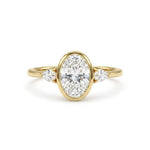 Oval cut Moissanite engagement ring with bezel-set 10.00 × 7.00 mm center stone, pear cut side stones, elegant yellow gold finish, and minimalist three-stone design.